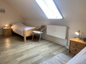 ein Schlafzimmer mit einem Bett, einem Stuhl und einem Fenster in der Unterkunft Huus Utspann in Nordstrand
