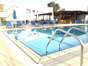 a large swimming pool with blue chairs and a hotel at Florea Hotel Apartments in Ayia Napa