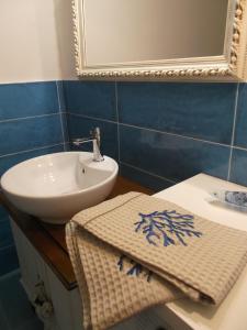 een badkamer met een wastafel, een spiegel en een handdoek bij La Vela suite in Orosei