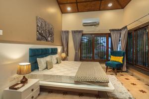 a bedroom with a bed and a blue chair at SaffronStays Verandah by the Valley, Panchgani - luxury villa and treehouse with beautiful valley and lake views in Panchgani