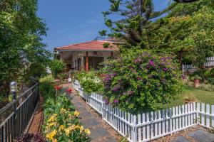 a white picket fence in front of a house with flowers at SaffronStays Verandah by the Valley, Panchgani - luxury villa and treehouse with beautiful valley and lake views in Panchgani