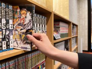una persona está buscando un libro de manga en un estante en Rinn Gion Yasaka en Kyoto