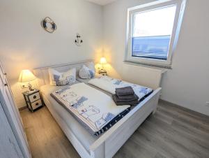 a bedroom with a white bed with a window at Ferienhaus Sellin in Ostseebad Sellin