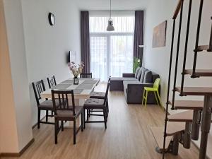 ein Wohnzimmer mit einem Tisch, Stühlen und einem Sofa in der Unterkunft Vízparti Silver X apartman in Siófok