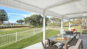 a white pergola on a patio with a table and chairs at Kendalls Beach House in Kiama