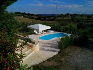 a pool with an umbrella and two chairs and a table and an umbrella at Villa Trullo Panorama in Locorotondo