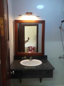 a bathroom sink with a mirror and a person taking a picture at Khách sạn Vườn Quốc gia Ba Bể in Bak Kan