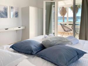 Cama blanca con almohadas azules y vistas al océano en Palm Suite Blue en Porto Heli