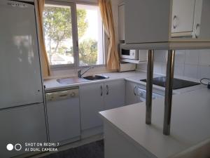 uma cozinha com armários brancos, um lavatório e uma janela em Apartment with amazing seeview in Miraflores Monte B em La Cala de Mijas