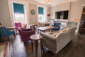 uma sala de estar com um sofá, cadeiras e mesas em Court Colman Manor em Bridgend