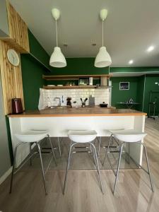 a kitchen with a large white counter and white chairs at Evergreen Apart in Almaty