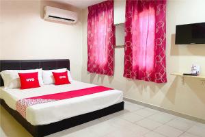 a bedroom with a bed with red pillows and pink curtains at OYO 90324 Muar Station Hotel in Kuah