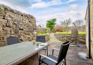 eine Terrasse mit einem Tisch, Stühlen und einer Steinmauer in der Unterkunft Red Lion House in Hartington