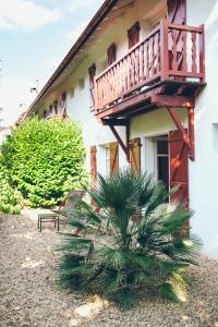 a house with a balcony and a palm tree in front at Hôtel Arcé in Saint-Étienne-de-Baïgorry