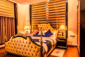 een vrouw op een bed in een hotelkamer bij Golden Tulip Headington in Muscat