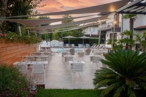 een patio met tafels en stoelen en een zwembad bij Hotel Tarabella in Forte dei Marmi