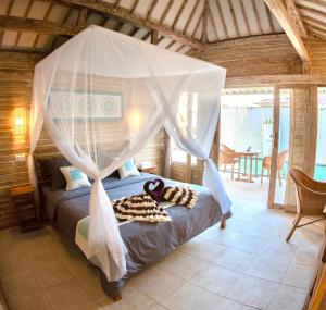 a bedroom with a bed with a mosquito net at GiliZen Resort - Private Pool Villas in Gili Air