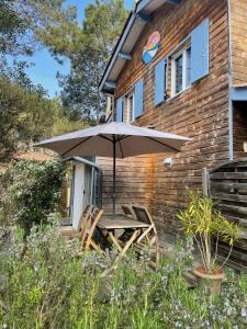 a table and chairs under an umbrella in front of a house at Le Petit Havre in Lacanau-Océan