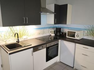a kitchen with white cabinets and a sink and a microwave at Holiday Home Tossens-3 by Interhome in Butjadingen OT Tossens