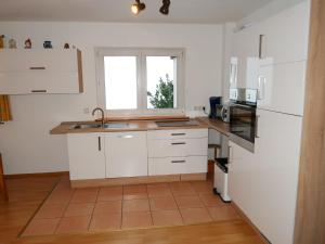 uma cozinha com armários brancos, um lavatório e uma janela em Apartment Mühlenmichelshäusle by Interhome em Hinterzarten