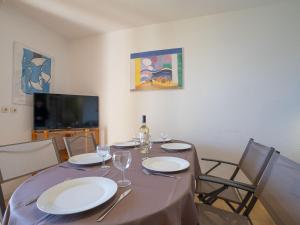 a table with plates and wine glasses and a television at Holiday Home Marina 1 by Interhome in Saint-Cyprien-Plage