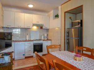 a kitchen with a table and a kitchen with white appliances at Holiday Home Mateja - KRK228 by Interhome in Kornić