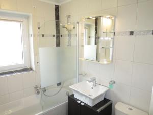 a white bathroom with a sink and a mirror at Apartment Panorama by Interhome in Berghofen