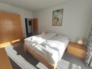 a bedroom with a bed with white sheets and a dresser at Apartment Allod Park Haus C E03 by Interhome in Davos