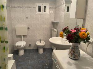 a bathroom with a toilet and a sink and a vase of flowers at Apartment Olivo - PGI128 by Interhome in Poggi +18 photos