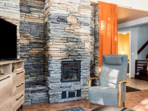 a stone fireplace in a living room with a chair at Holiday Home Levijoutsen by Interhome in Levi