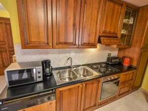 cocina con armarios de madera, fregadero y microondas en Apartment Mariella by Interhome, en Mazzo di Valtellina