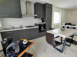 ジェーラ・ラーリオにあるApartment Titti - GLA133 by Interhomeのキッチン(黒いキャビネット、テーブル、椅子付)