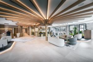 een lobby met witte meubels en een groot plafond bij Quellenhof See Lodge in Saltusio