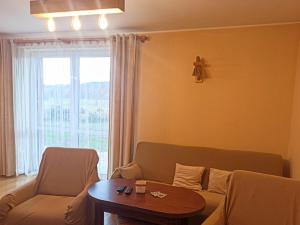 a living room with a couch and a table and a window at Holiday Home Lgota by Interhome in Witanowice