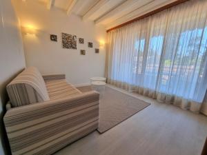 salon z kanapą i dużym oknem w obiekcie Apartment Hermitage-5 by Interhome w mieście Porto Valtravaglia