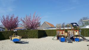 un parque infantil en la arena con dos columpios en Camping Caravaning Les Cerisiers Berck sur mer, en Verton