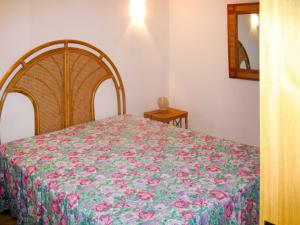 sypialnia z łóżkiem z kwiatowym kocem w obiekcie Holiday Home BINI - REI210 by Interhome w mieście Costa Rei