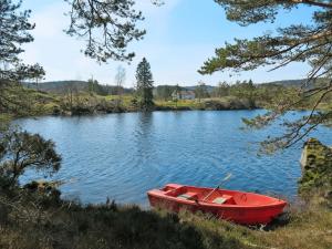 um barco vermelho sentado no meio de um lago em Holiday Home Der ute - SOW441 by Interhome em Brådland