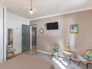 a bedroom with a bed and two chairs and a tv on the wall at Holiday Home Polpu by Interhome in Sari Solenzara