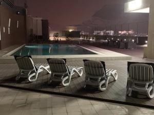 een groep stoelen naast een zwembad bij Golden Tulip Headington in Muscat