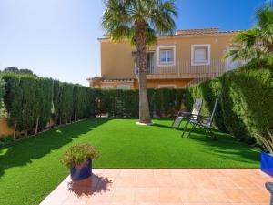 a lawn with a palm tree and a house at Apartment Pinazo by Interhome in Cumbre del Sol