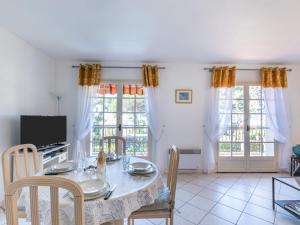 ein Esszimmer mit einem Tisch, Stühlen und Fenstern in der Unterkunft Apartment Beau Rivage by Interhome in Carqueiranne