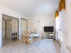 ein Esszimmer mit einem Tisch, Stühlen und einem TV in der Unterkunft Apartment Beau Rivage by Interhome in Carqueiranne