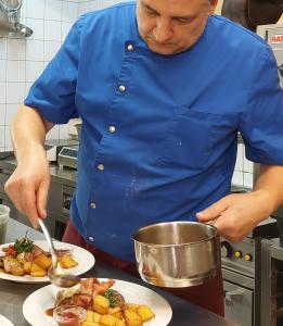 un hombre con camisa azul preparando comida en una cocina en Bio-Bauernhof-Hotel Matlschweiger, en Lassing