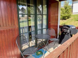 a patio with two chairs and a grill on a porch at Holiday Home Holiday Hill 67 by Interhome in Lauterwasser