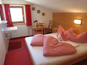 1 dormitorio con 1 cama con almohadas rojas y blancas en Apartment Alpenhof-3 by Interhome, en Kappl