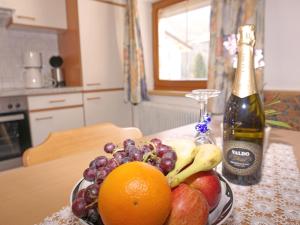 un bol de fruta en una mesa con una botella de champán en Apartment Alpenhof-3 by Interhome, en Kappl