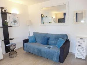 ein blaues Sofa im Wohnzimmer mit Spiegel in der Unterkunft Apartment La Nuit de Mai-5 by Interhome in Saint-Aygulf