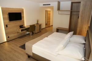 a bedroom with a bed and a desk and a television at Hotel Lindleinsmühle in Würzburg