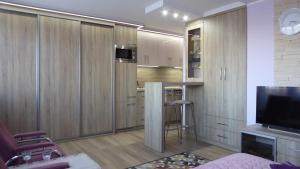 グディニャにあるApartament Mario Skwer Kościuszkiのリビングルーム(木製キャビネット付)、キッチンが備わります。
